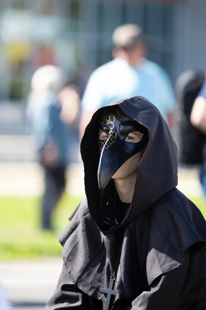 A boy dressed as a plague doctor stares down observers.
