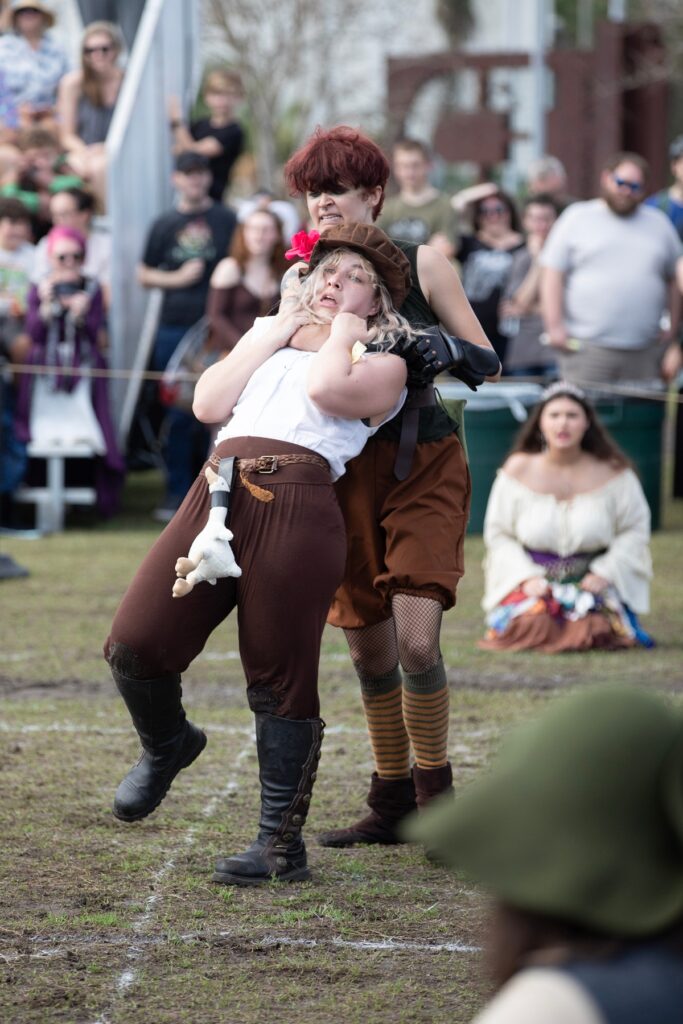 A fighter in the Living Chessboard tournament attempts to strangle her opponent.