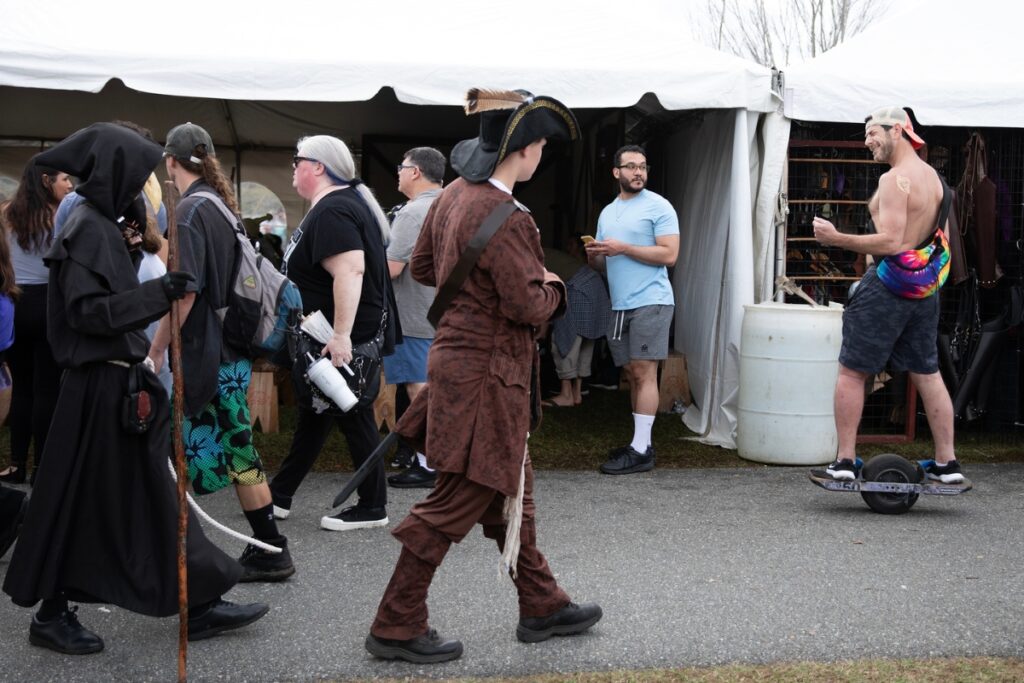 A man on an electric scooter zooms past booths at the faire.