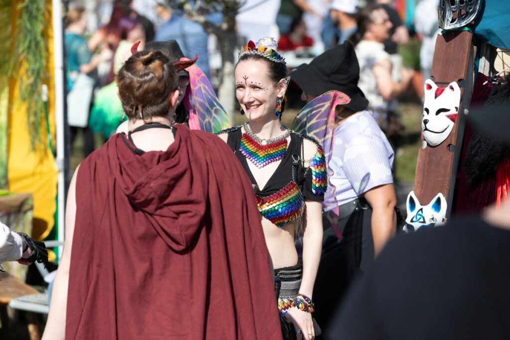 A woman dressed as a fairy speaks to another wearing horns.