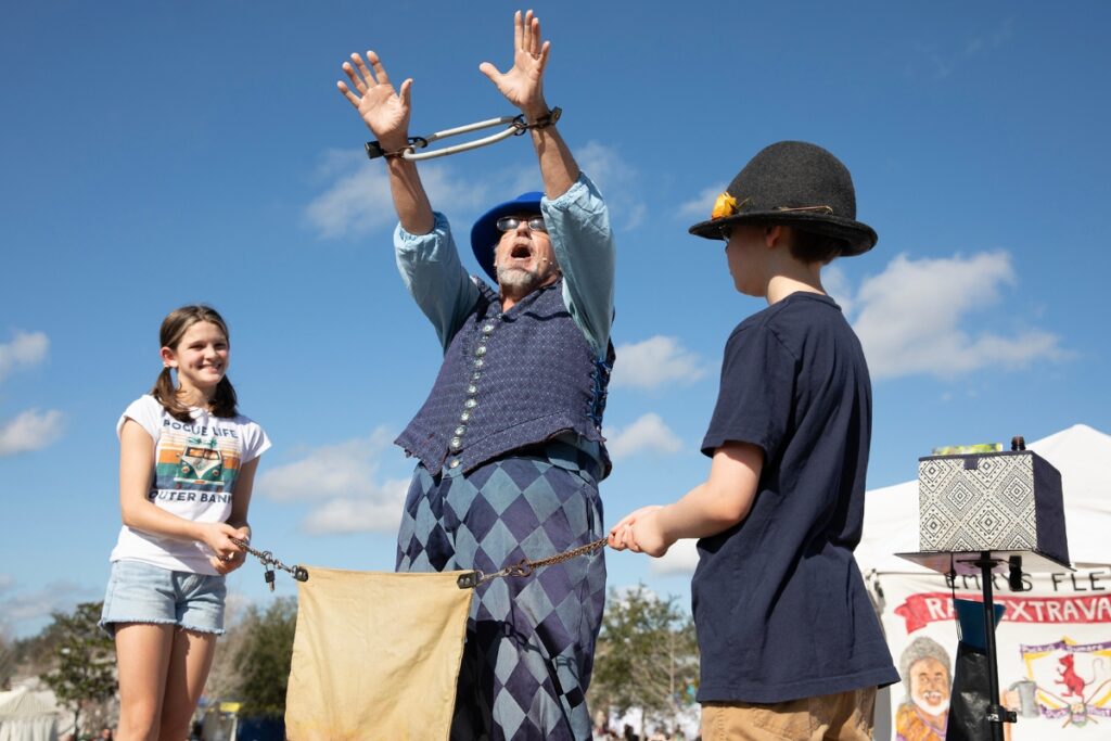 Charlee Guadagno of Newberry, left, and Oliver Crump of Newberry, right, help rat catcher Emrys Fleet escape from handcuffs.