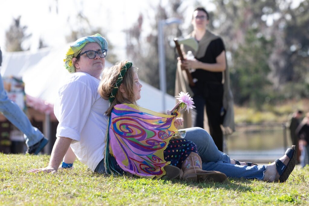 Festival attendees relax upon a grassy mound.
