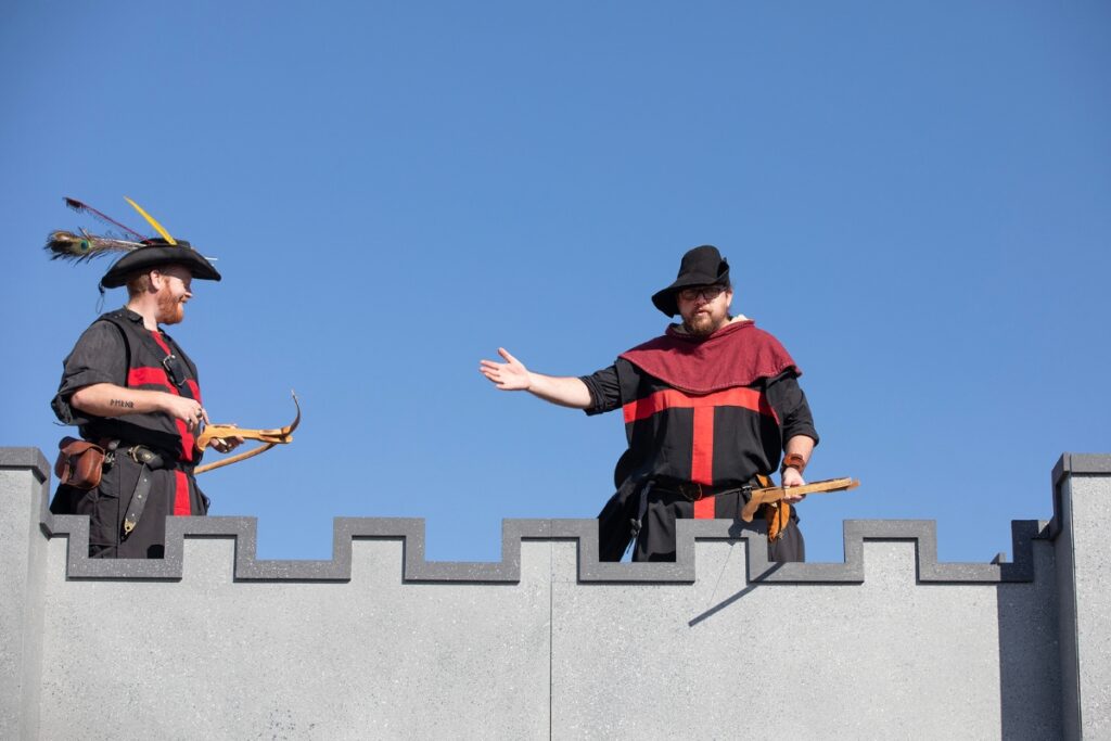 Guards standing atop a plywood fortress shoot mini marshmallows at new arrivals.