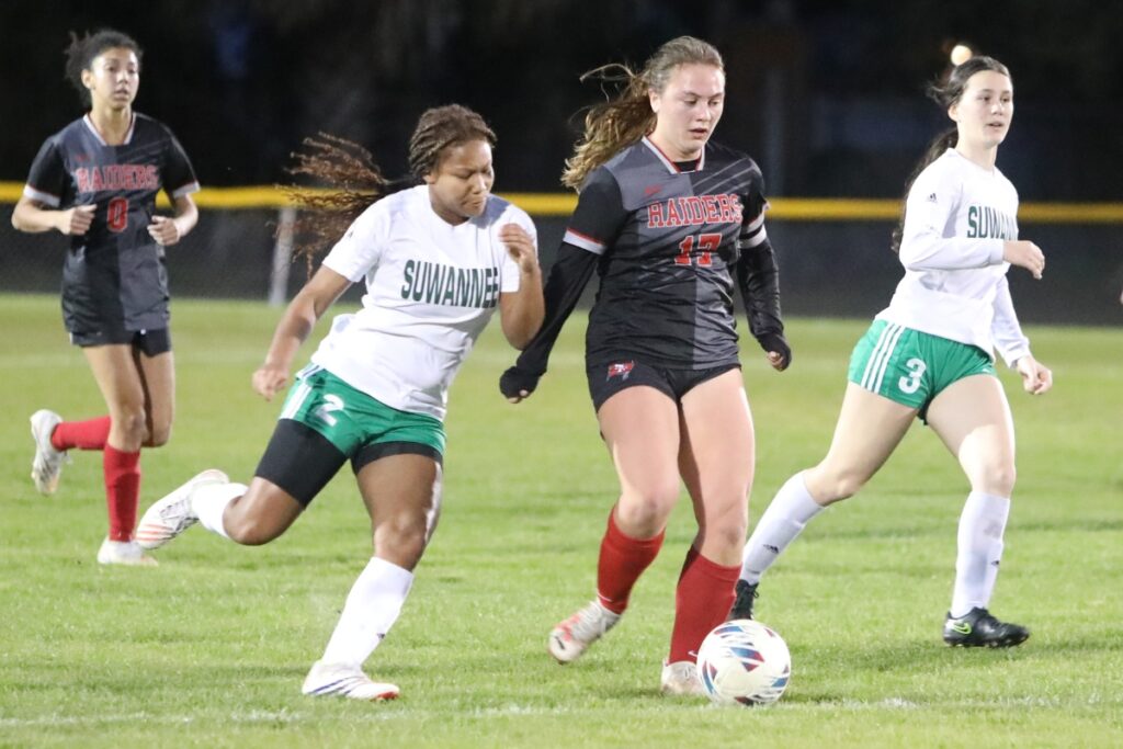 Santa Fe's Maggie Boone dribbles past Suwannee's Kayla Federick-Woods (2) and Lydia Gunter (3).