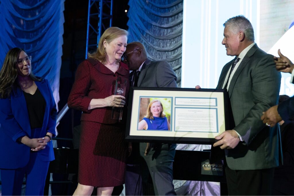 Susan Crowley, in red, accepts the chamber’s legacy award from outgoing board chair Domenic Scorpio.