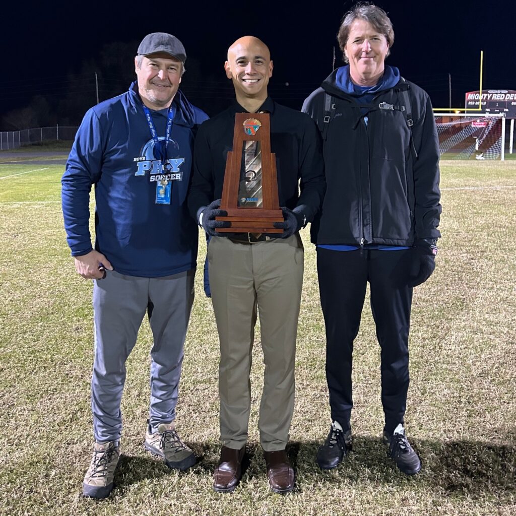 The P.K. Yonge coaching staff holds the 3A-District 4 boys soccer championship trophy after a 3-1 win over Williston.