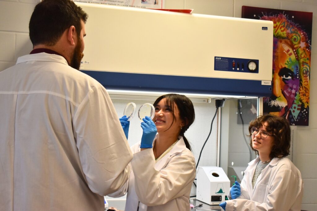 Jenny Nguyen shows Tyler Wells some colorful samples, with Halle Reeves looking on.