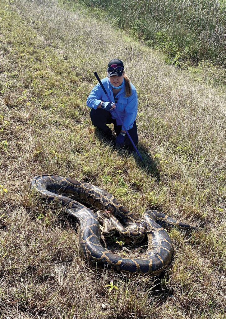 Melissa Miller sits beside a python.