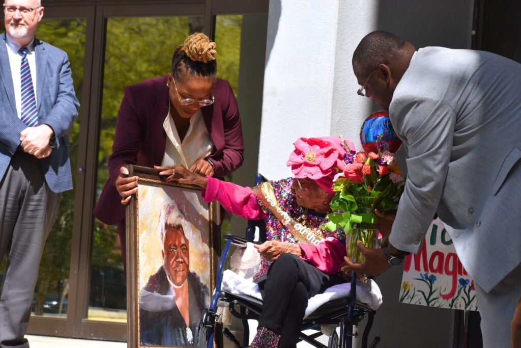 Crystal deGregory presents a portrait to Magnolia Jackson for her 106th birthday.
