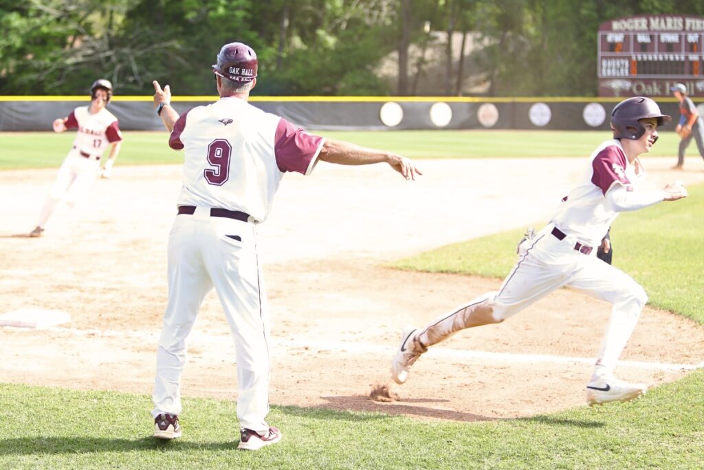 Oak Hall coach Kevin Maris waves in Jackson Beach (right) and Harrison Beach as the Eagles went ahead 2-0 over P.K. Yonge in the bottom of the second inning.