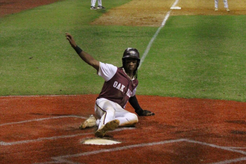 Oak Hall's Medley Darion slides into home for the first score of the game.