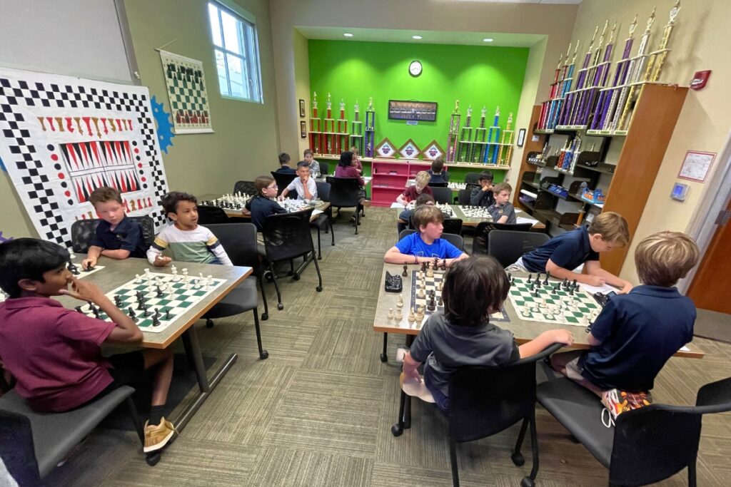 Students practice at the Oak Hall Chess Club, ringed by trophies from past successes.