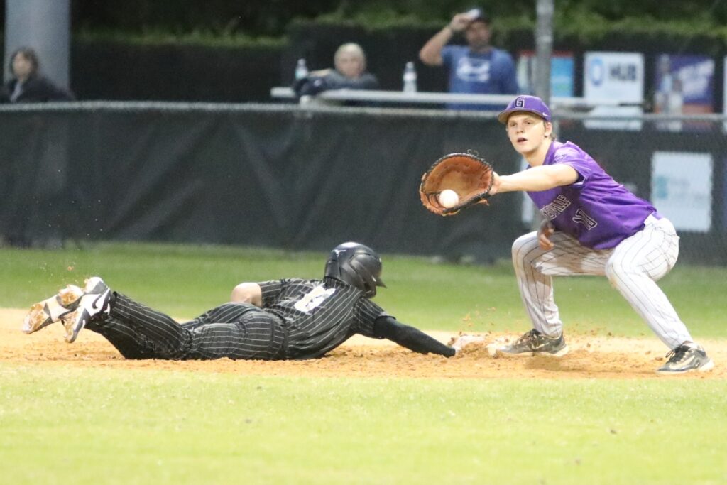 Buchholz's Hudson Sapp dives safely back to first base in the bottom of the third inning against Gainesville's Connor Kemph.