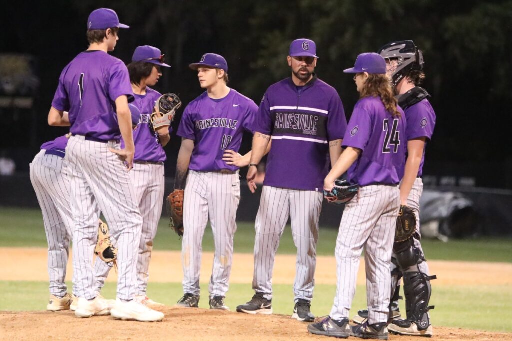 Gainesville coach Adrian Ramos (third from right) talks to pitcher Chance Mandarino (24) and the Hurricanes' infield during Buchholz's seven-run third inning.