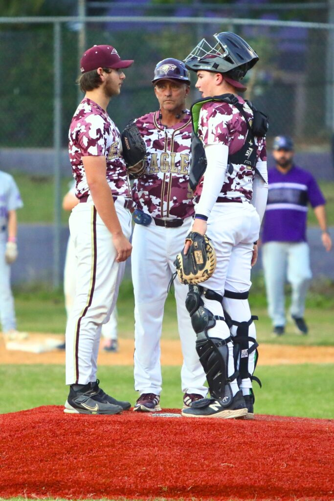 Oak Hall coach Kevin Maris (center) talks with pitcher Troy Freeman (left) and catcher Brody Beaupre against Gainesville on Monday.