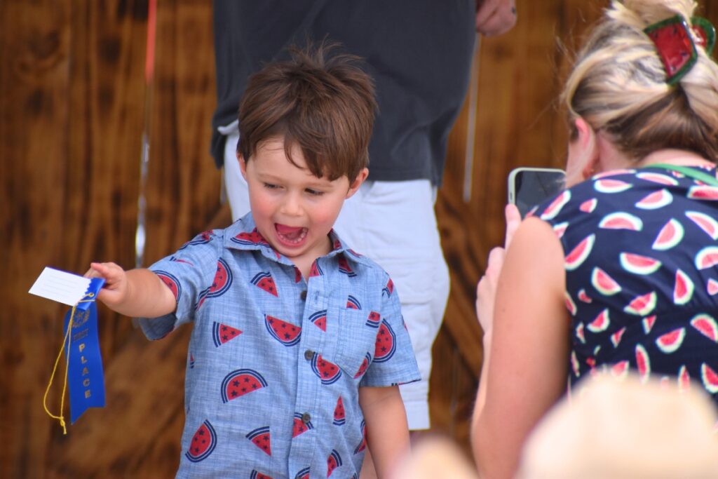 Bo Gibson exclaims over his blue ribbon after winning the hog calling contest.