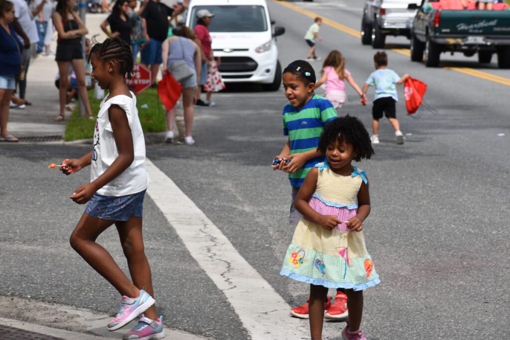 Children gather candy out of the street during the parade.