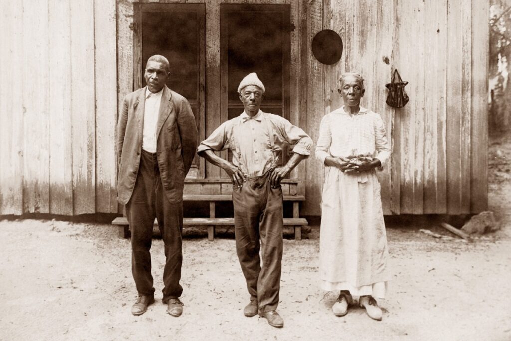 Freedmen standing in front of the old kitchen. In 1860 there were 66 enslaved people working here. This may be William and Louisa Watts standing on the right. We believe the taller man on the left might be Bennet Kelley. If we're correct, all three had been enslaved here.