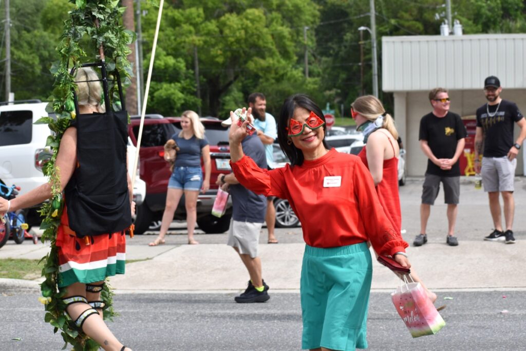 Rainbow Young waves as she walks with other representatives of Bosshardt Realty in the Newberry Watermelon Festival parade.