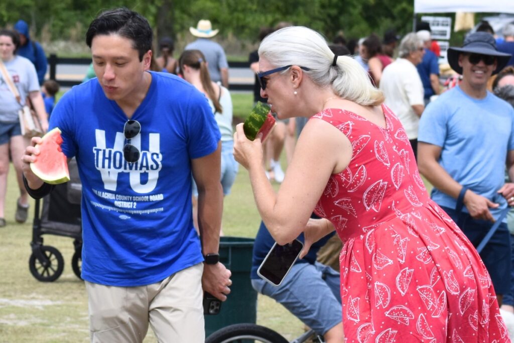 School Board candidate Thomas Vu and Alachua County Commissioner Anna Prizzia eat watermelon at the festival.