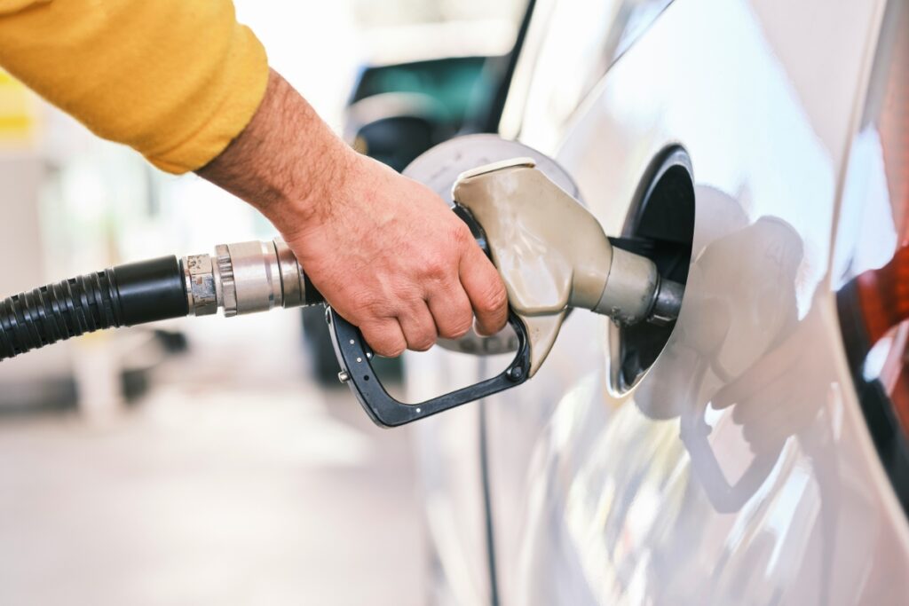 Person pumps gas into white car.