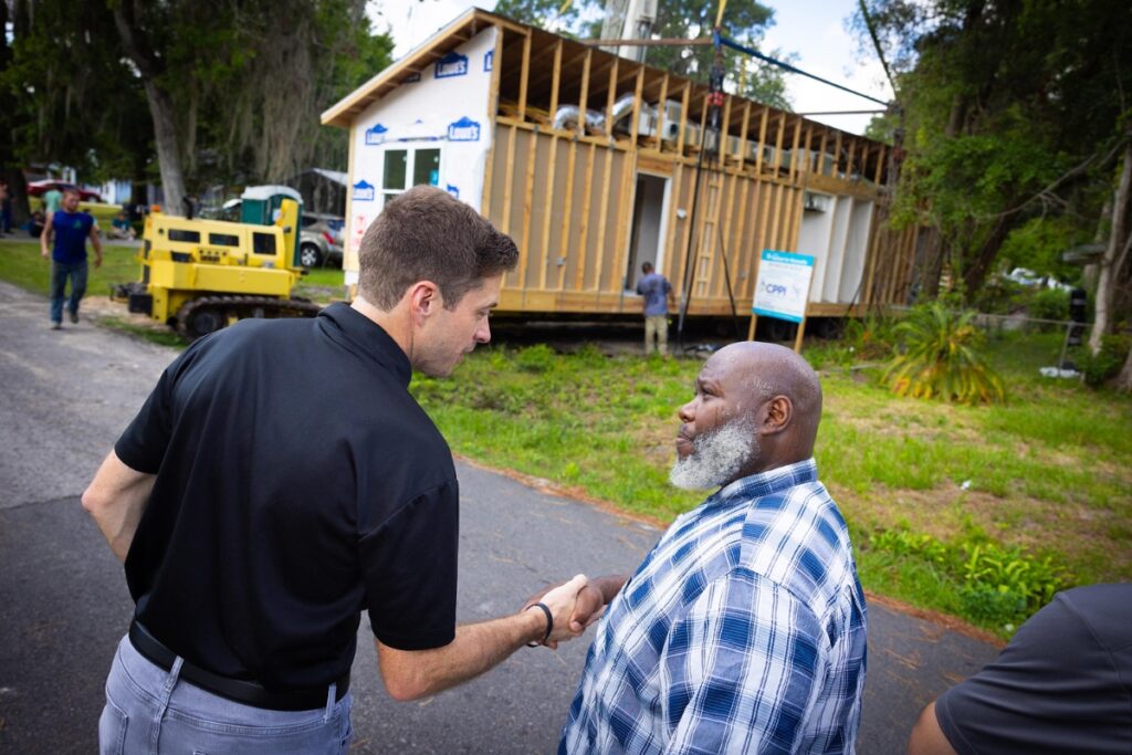 Toikeith Reynolds (right), homeowner and recipient of the Alachua Habitat for Humanity house shakes hands with Bryan Harrington, vice president/regional manager of the North Central Florida region