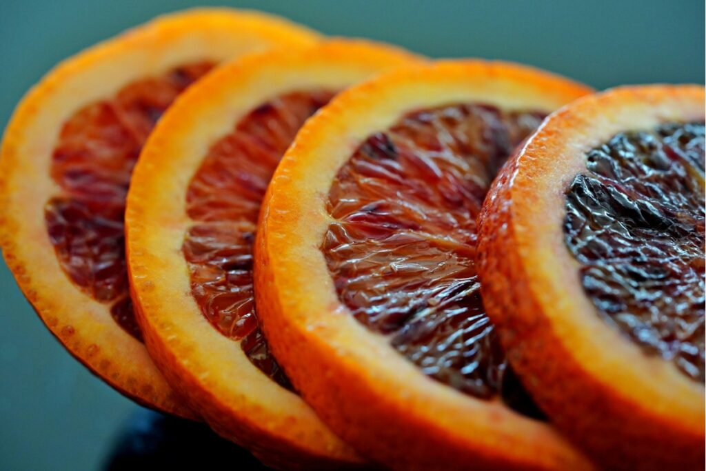 Slices of blood oranges sit on top of each other.