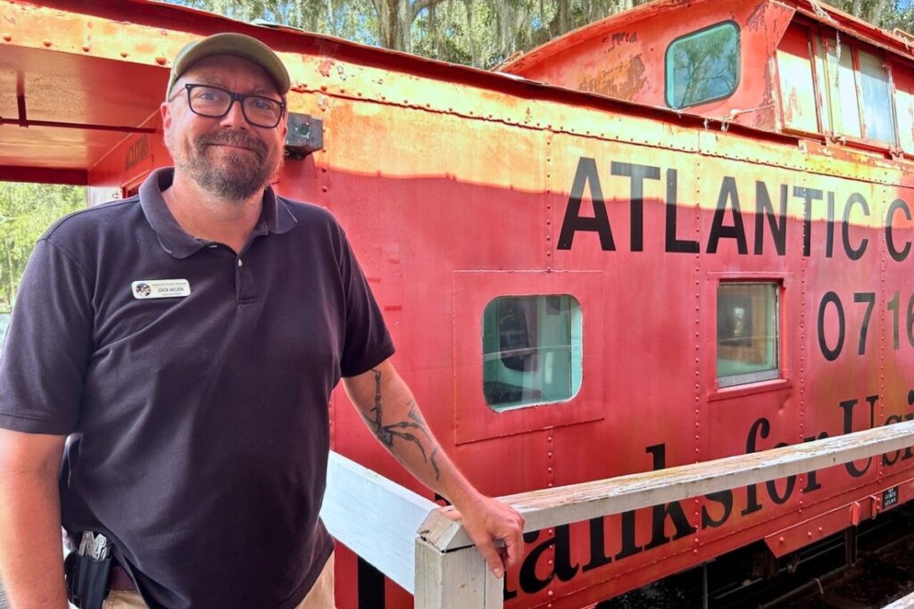 Associate Director Erick Nielsen in front of an old railroad car on the property.