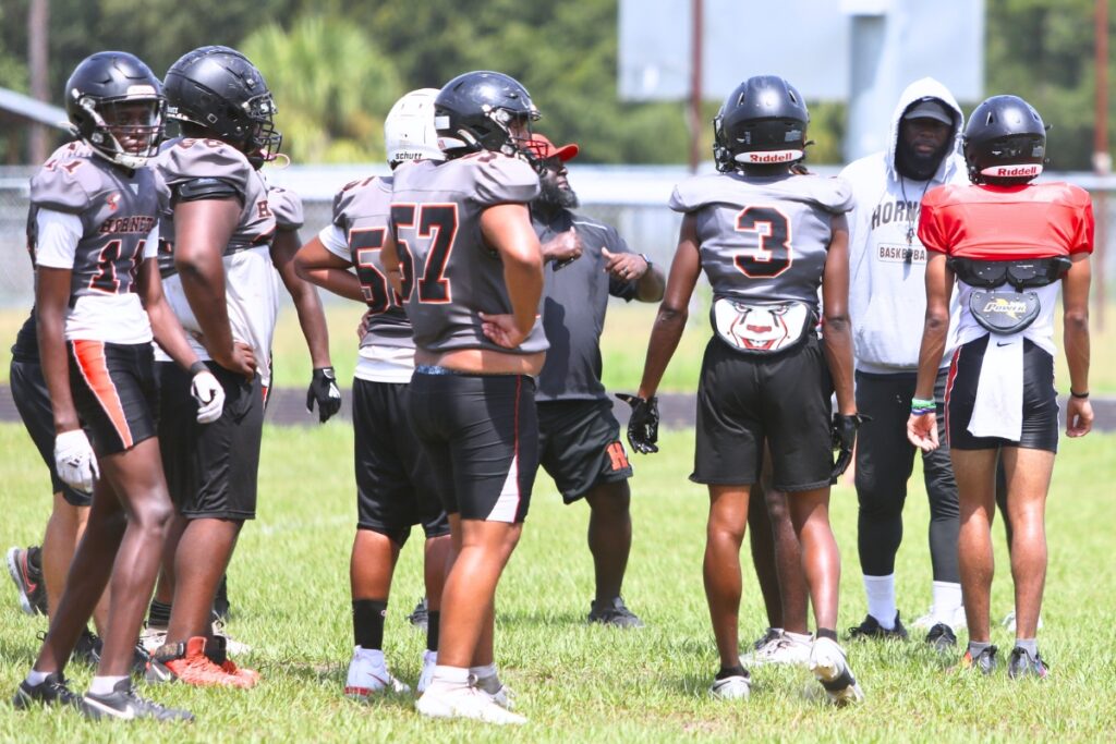 Hawthorne coach Cornelius Ingram (hoodie) talks to his quarterback during practice on Wednesday.