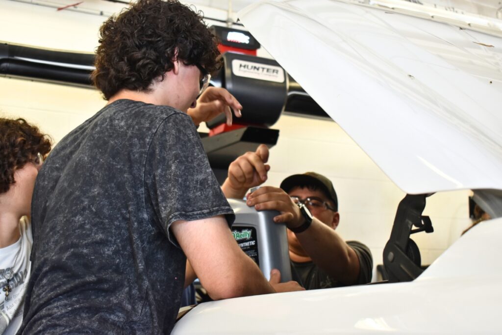 Loften High School students change a car's oil during class.