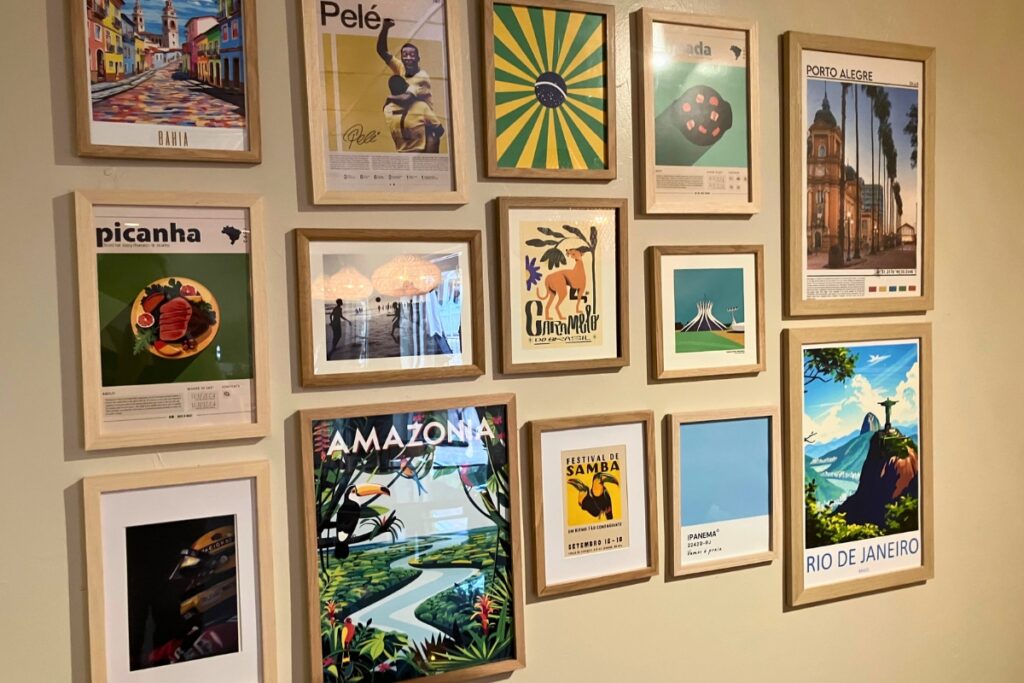 A variety of art displaying scenes from Brazilian culture hanging on the wall inside Samba. 