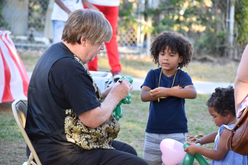 MeetMagicMike folds a balloon dog for a child.