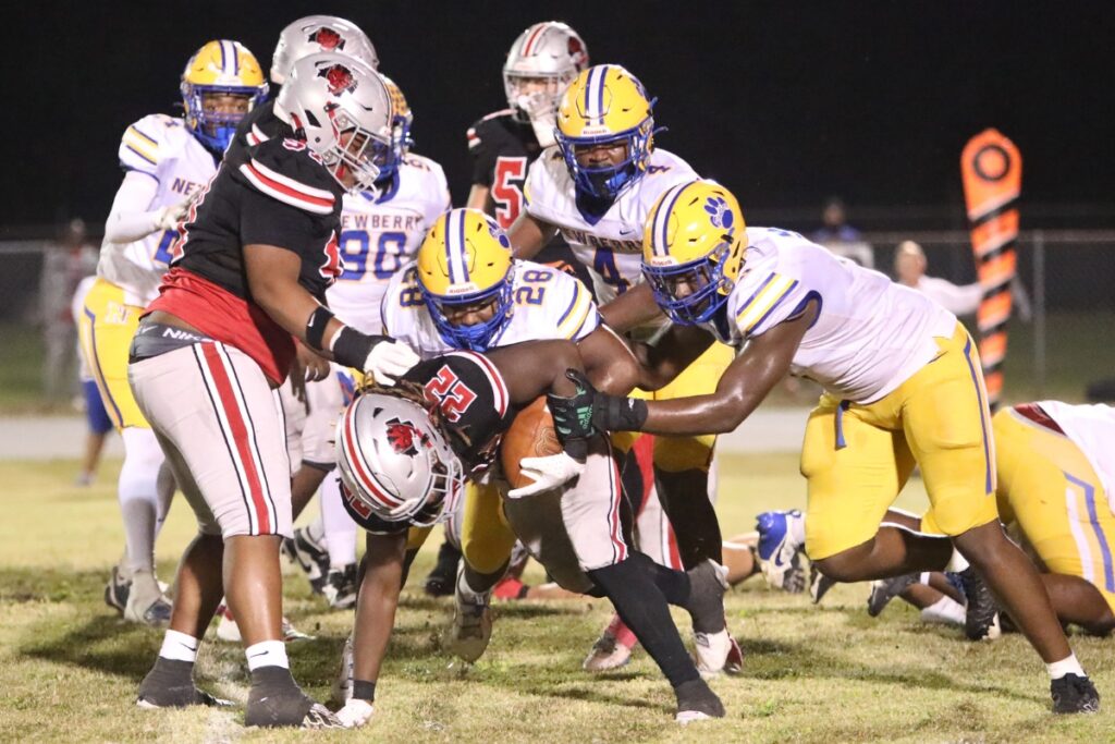 Newberry's Davon Rim (28) and Mykah Newton (9) bring down Williston's Jamari Williams (22).