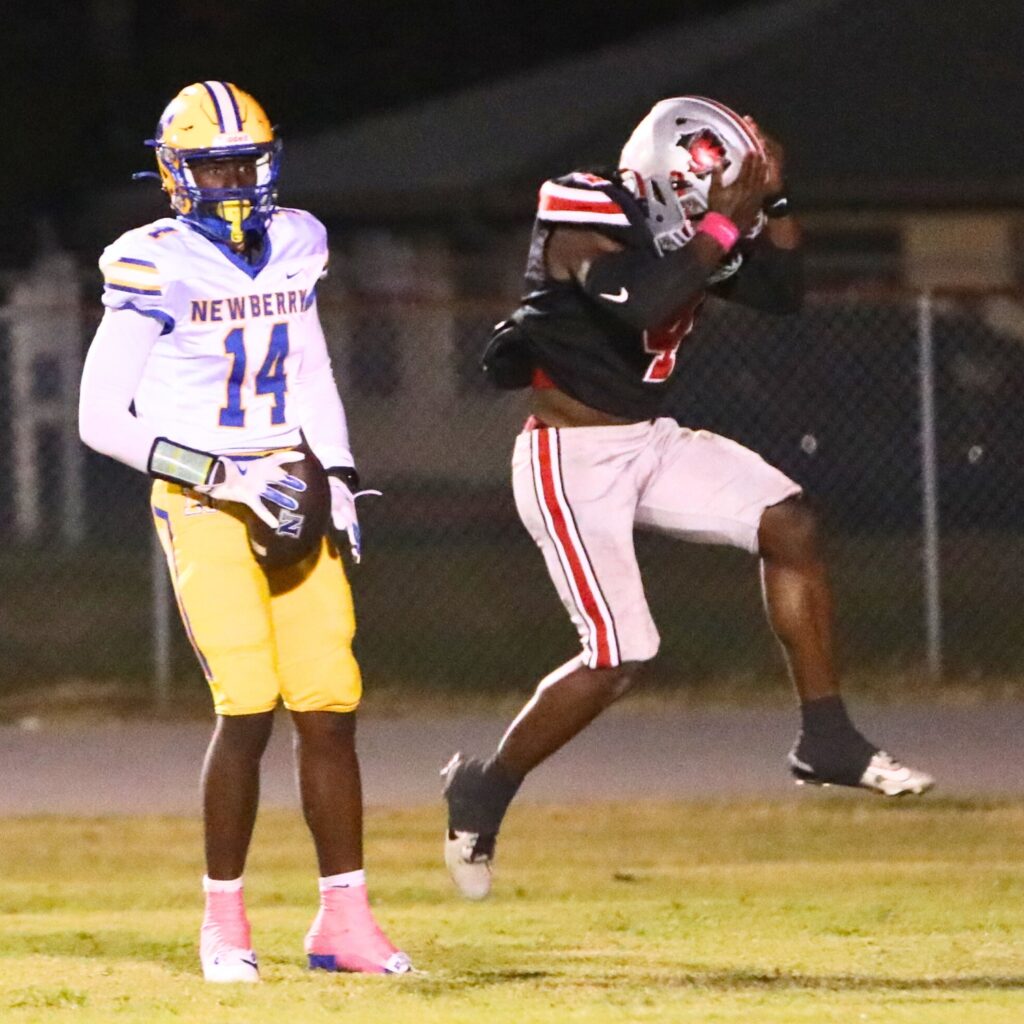 Newberry's Hayden Moore (14) got past Williston's Kameryn Manneh (4) to score the first touchdown of the game.