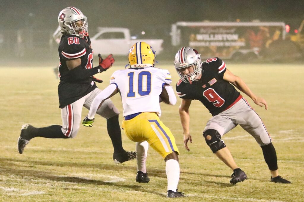Newberry's Jamarcus Wimberly (10) tries to run past Williston's Namari Collins (60) and Ryan Gagne (9) on the opening kickoff return.