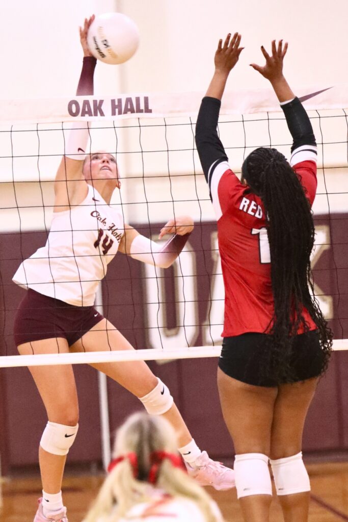 Oak Hall's Kendylle Bishop (14) with a hit against Chanitey James (11) on Tuesday.