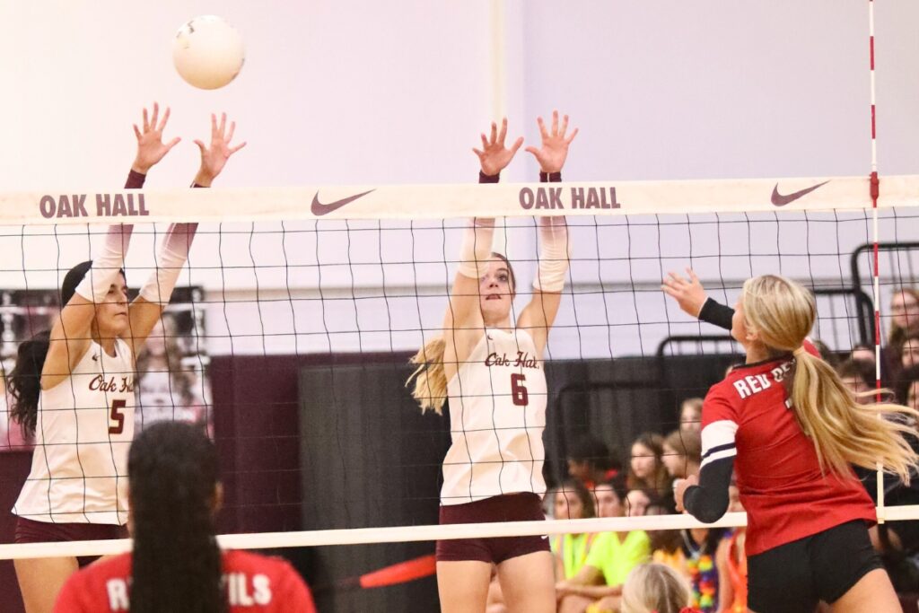 Williston's Ryleigh Hiers (1) with a hit against Oak Hall's Shyla Akri (5) and Hannah Timm (6) on Tuesday. Photo by C.J. Gish