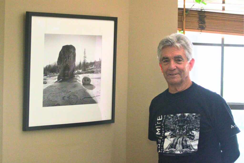 Batista poses with a piece of art in his home by mentor and former professor Jerry Ulesmann.