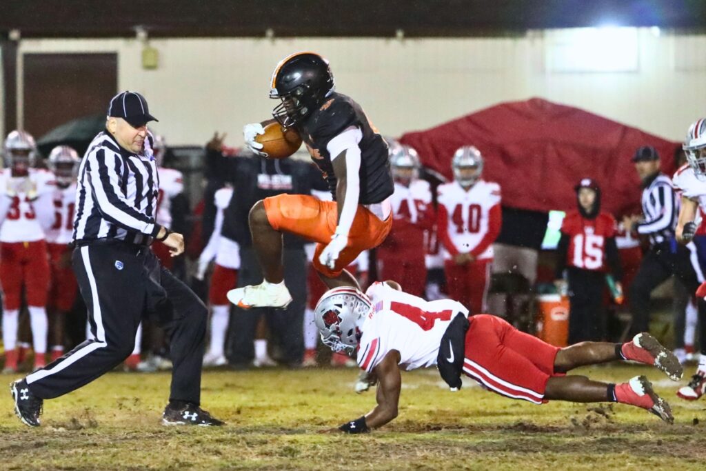 Hawthorne's Keenon Johnson (9) hurdles Williston's Kameryn Manneh (4).