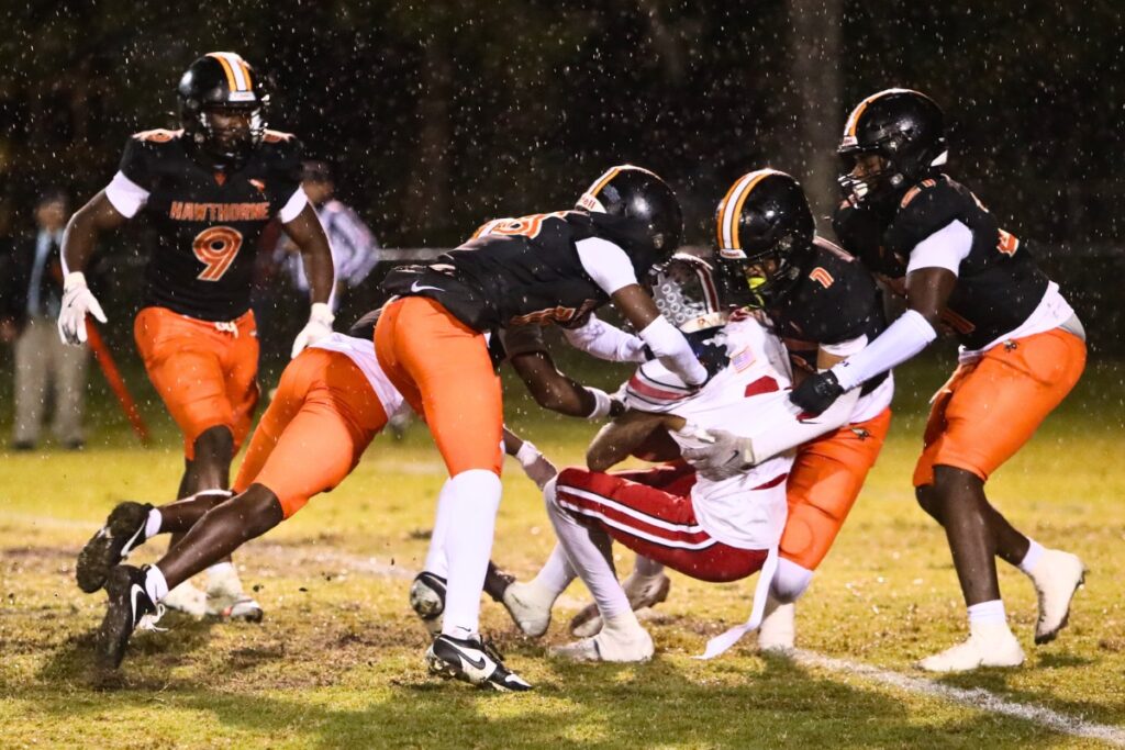 Williston's Giovanni Wright gets swarmed by Hawthorne players on a first-quarter kickoff return.