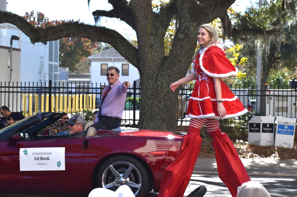 Commissioner Ed Book points to his daughter on stilts in the Gainesville holiday parade.