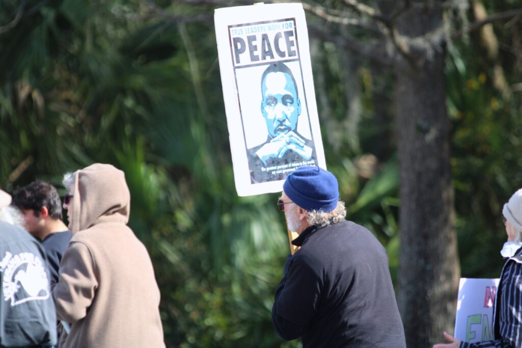 An MLK Day Parade participant holds a sign reading 'True Leaders Work for Peace.' Photo by Lillian Hamman