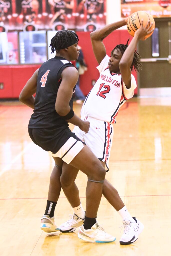 Hawthorne's Chasion Wilson (4) with tight defense on Williston's Azyron Johnson (12). Photo by C.J. Gish