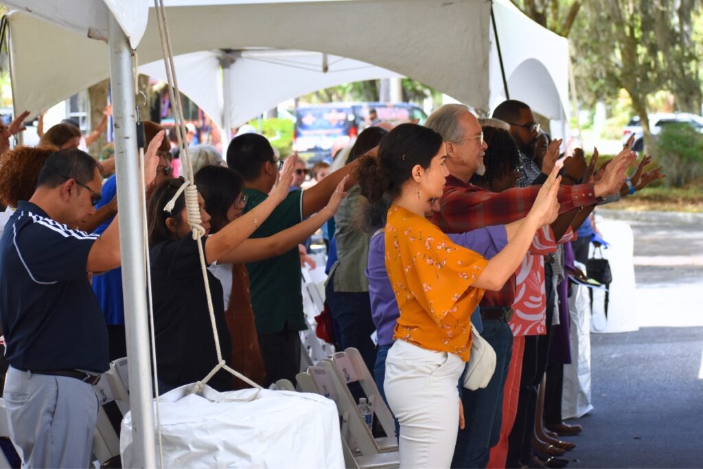 Attendees stretch out their hands in Bishop Stokes' blessing on the building. Photo by Glory Reitz