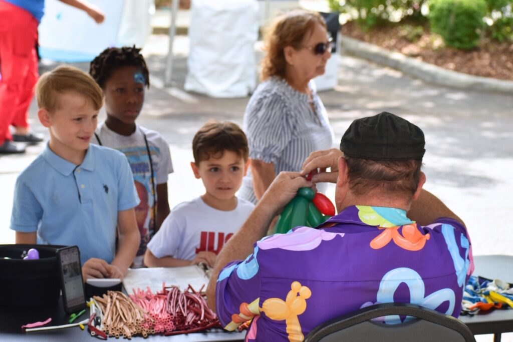 Children watch a balloon being folded. Photo by Glory Reitz