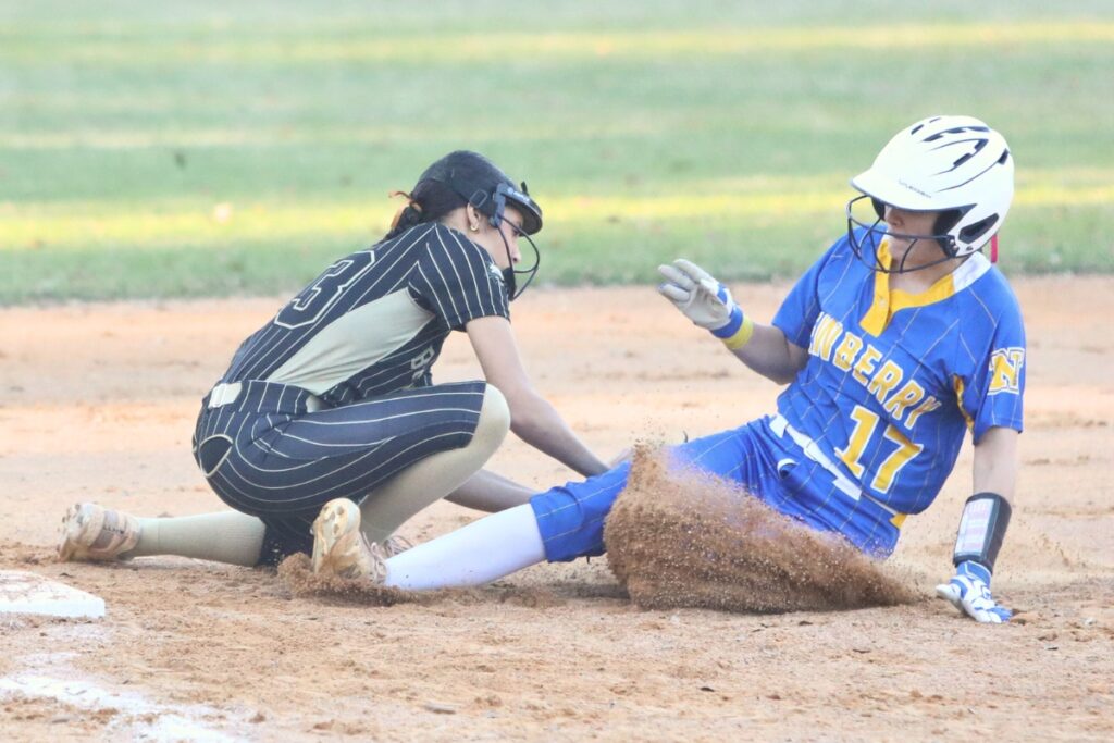 Newberry's Olivia Tharp (17) gets tagged out at third base by Buchholz's Jayda Cooper (33). Photo by C.J. Gish