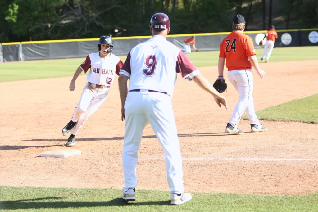 Oak Hall's Connor Cross waved home by coach Kevin Maris for a third-inning run against Hawthorne. Photo by C.J. Gish