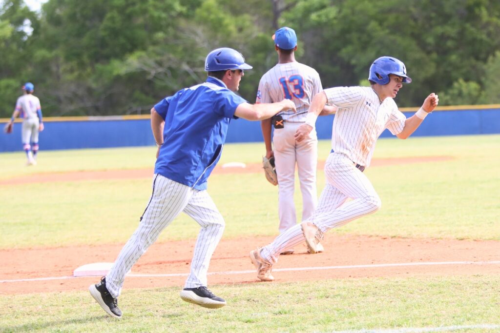 St. Francis Catholic's head coach Ryan Brown (left) waves Dylan Diaz in for a score against P.K. Yonge in the first inning. Photo by C.J. Gish