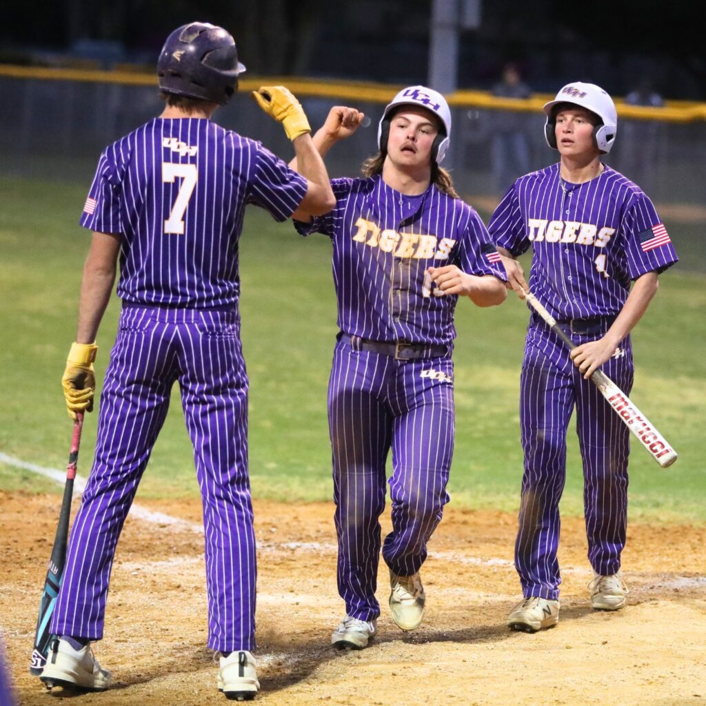 Union County's Foster Smith (7) congratulates Trenton Klein (15) and Evan Roberts (4) after the two score in the third inning against Trenton. Photo by C.J. Gish