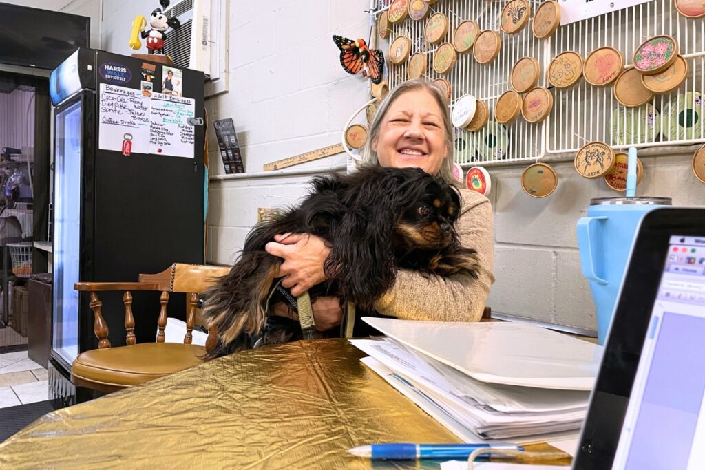 Cindy Bevilacqua sits at her business, CindyBGoods, with a binder that contains emails, permits and surveys from the ordeal to get a foundation permit. Photo by Seth Johnson